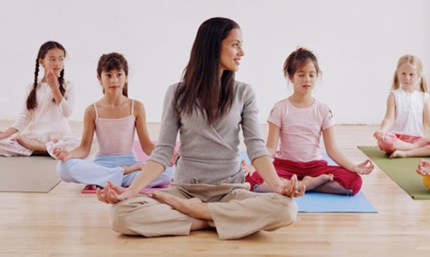 Woman teaching children (7-10) yoga