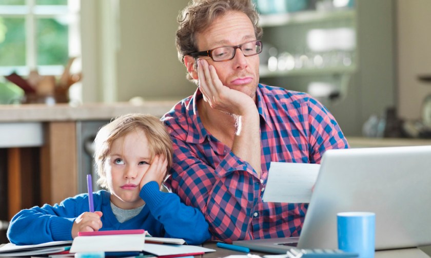 Bored father and son working at table